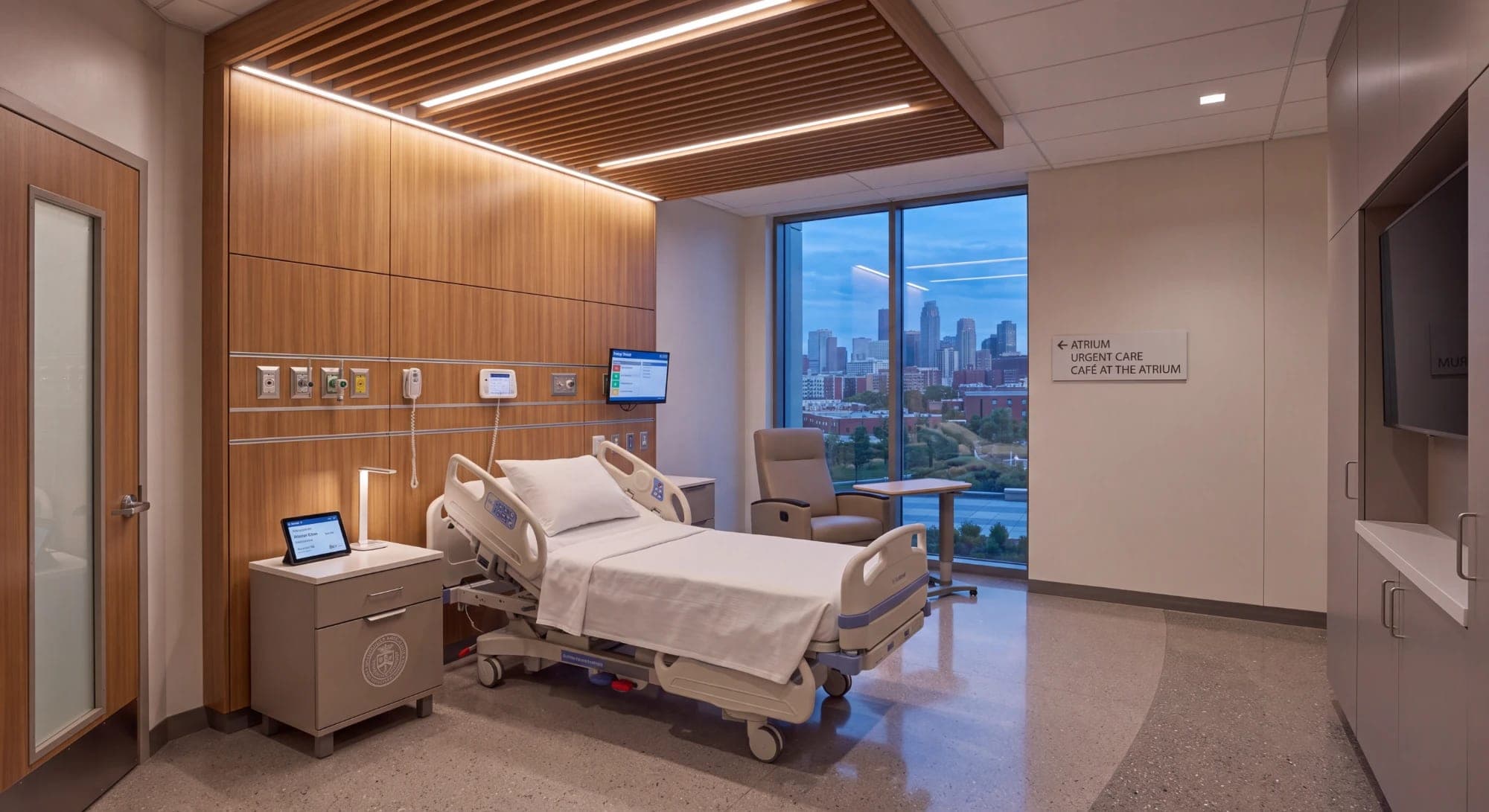 Render of a hospital patient room with timber panelling and a window view of the city at dusk